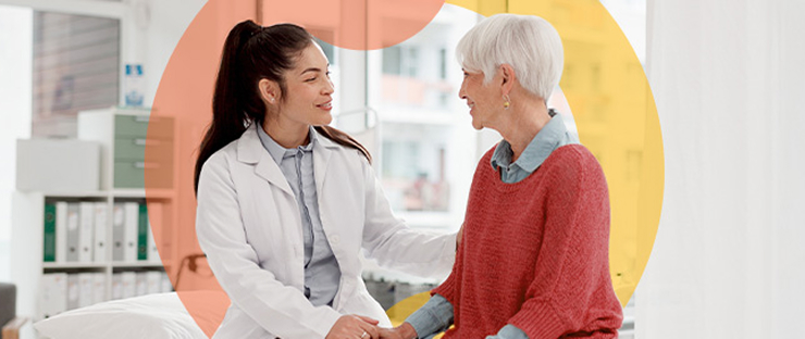 Female doctor sitting next to older female patient on exam table Female doctor sitting next to older female patient on exam table